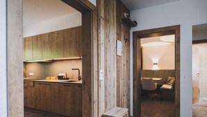 A modern kitchen with wooden cabinets, a built-in stove, and a small wooden stool. - Chalet Carina by we rent (Zell am See)