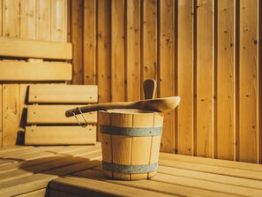A wooden sauna bench and a wooden bucket with a wooden spoon resting on it. - Chalet Carina by we rent (Zell am See)