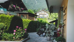 A courtyard with a stone pathway, potted plants, and a wooden bench. - Chalet Carina by we rent (Zell am See)