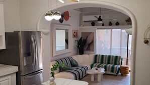 Una cocina moderna con refrigerador integrado, un comedor con mesa de mármol y una sala de estar con sofá y televisor.
