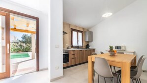 A modern kitchen with wooden cabinets, a dining table with chairs, and a view of a swimming pool. - Elegant Villa With Private Pool in San Teodoro (San Teodoro)