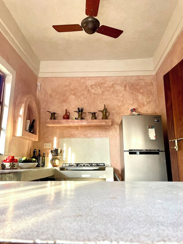 Una cocina con ventilador de techo, refrigerador y encimera con varios objetos.