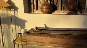 A rustic interior with a wooden chest, a brass lantern, and a ceramic jug on a shelf.