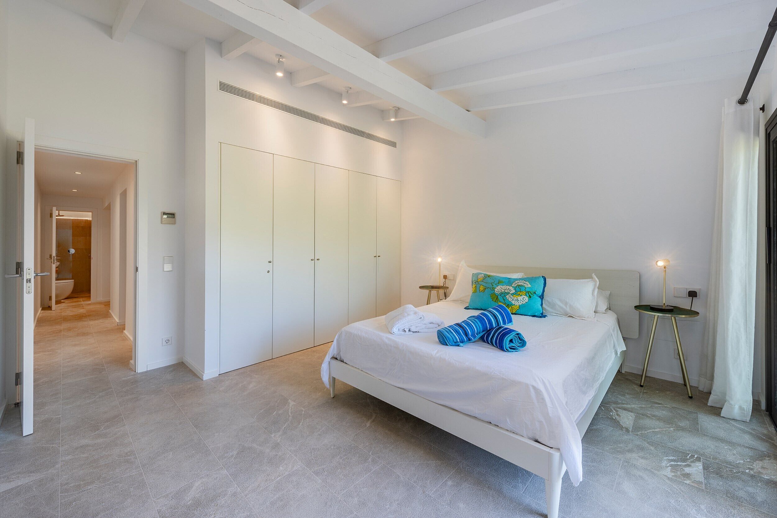 A bedroom with a bed, a wardrobe, a bedside table, and a lamp.