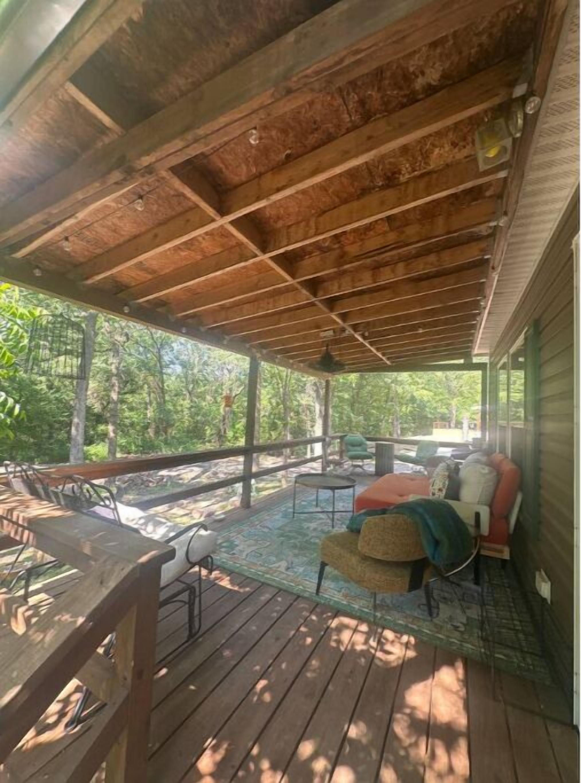 A covered porch with wooden flooring, a table, chairs, and a sofa.