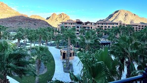Un resort con piscina, palmeras y montañas al fondo.