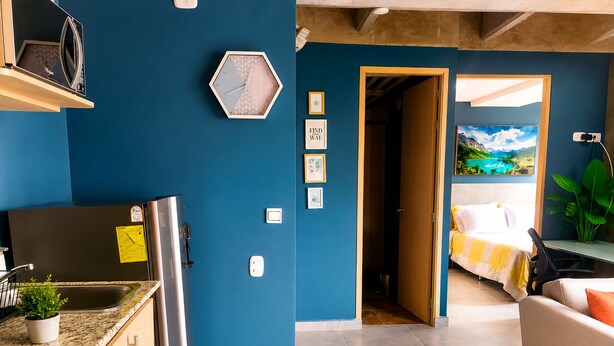 A modern kitchen with a stainless steel refrigerator, a microwave, and a sink. There is a wooden cabinet with a plant on the counter. - Stylish Laureles Loft in Medellin (Medellín)