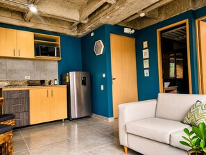 A modern kitchen with a stainless steel refrigerator, wooden cabinets, and a microwave. - Stylish Laureles Loft in Medellin (Medellín)