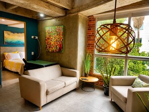 A modern living room with a sofa, a coffee table, and a hanging light fixture. - Stylish Laureles Loft in Medellin (Medellín)
