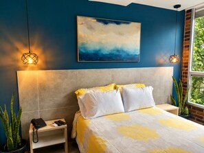A bedroom with a bed, bedside tables, a telephone, and a painting on the wall. - Stylish Laureles Loft in Medellin (Medellín)