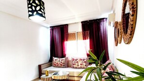 A modern living room with a sofa set, a coffee table, a hanging light fixture, and a large plant.