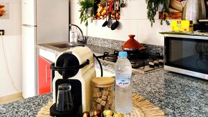 A kitchen with red and white cabinets, a microwave, a coffee maker, a water bottle, and a woven placemat with chocolates.