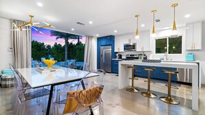 A modern kitchen with a central island, bar stools, and a view of the outdoors.