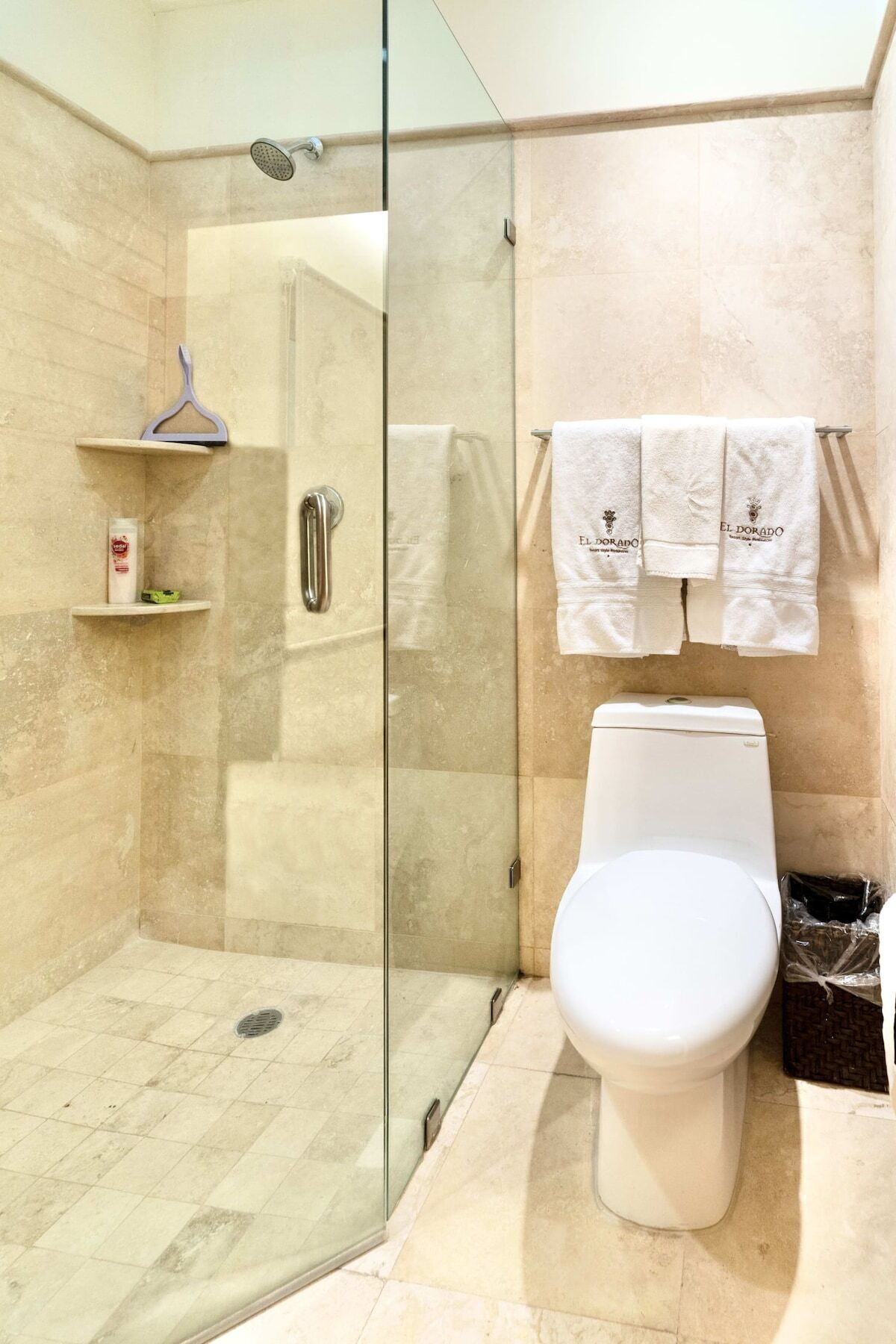 A modern bathroom with a glass-enclosed shower, a toilet, and two white towels hanging on a rack.