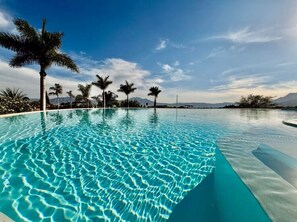 A clear swimming pool with palm trees and mountains in the background. - ANANA El Dorado 203 (Ajijic)