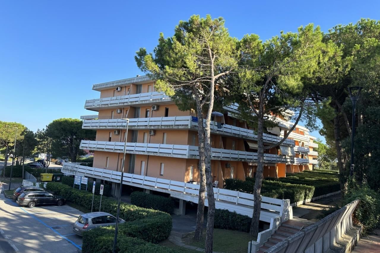 A multi-story hotel with balconies, a parking area, and well-maintained landscaping.