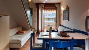 Un ambiente compatto con divano, tavolo da pranzo e ventilatore a soffitto.