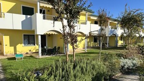 A yellow building with a balcony, a small garden, and a paved walkway. - Residence Ducale three-room apartment E16 C6*+ for 5 people (Bibione)