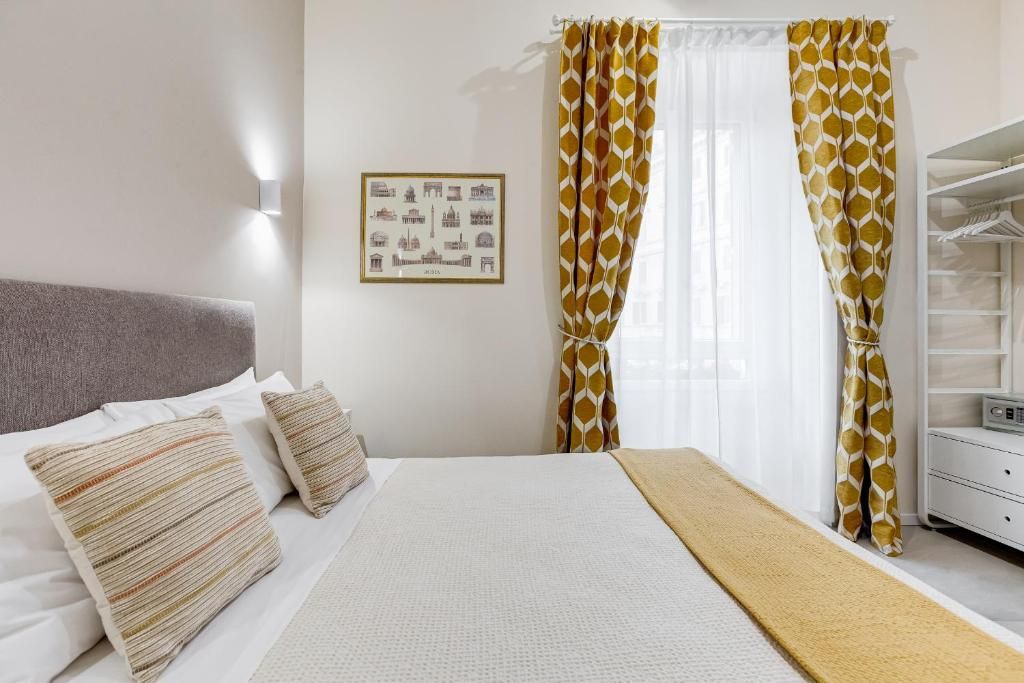 Ein Hotelzimmer mit einem Bett, einem Nachttisch, einer Wandleuchte und Vorhängen.