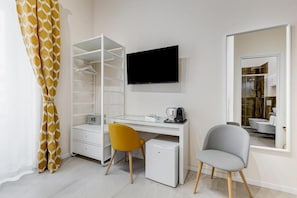 A modern room with a white desk, a flat-screen TV, a small refrigerator, and a yellow chair. - SCIPIONI 4O GUESTHOUSE (Rome)