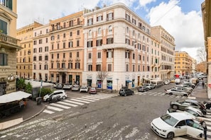 A street view with a row of parked cars, a pedestrian crossing, and buildings with classical architecture. - SCIPIONI 4O GUESTHOUSE (Rome)
