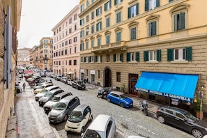 A street view with parked cars, buildings, and a pizzeria with a blue awning. - SCIPIONI 4O GUESTHOUSE (Rome)