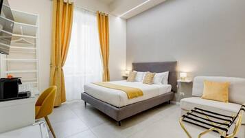 A modern hotel room with a bed, a desk, a chair, and a sofa.