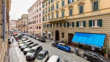 A street view with parked cars, buildings, and a pizzeria with a blue awning.