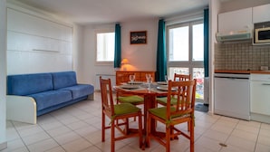 A compact living space with a dining area, kitchenette, and a blue sofa.