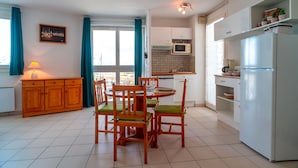A compact kitchen with a dining area, featuring a wooden cabinet, a microwave, and a refrigerator.