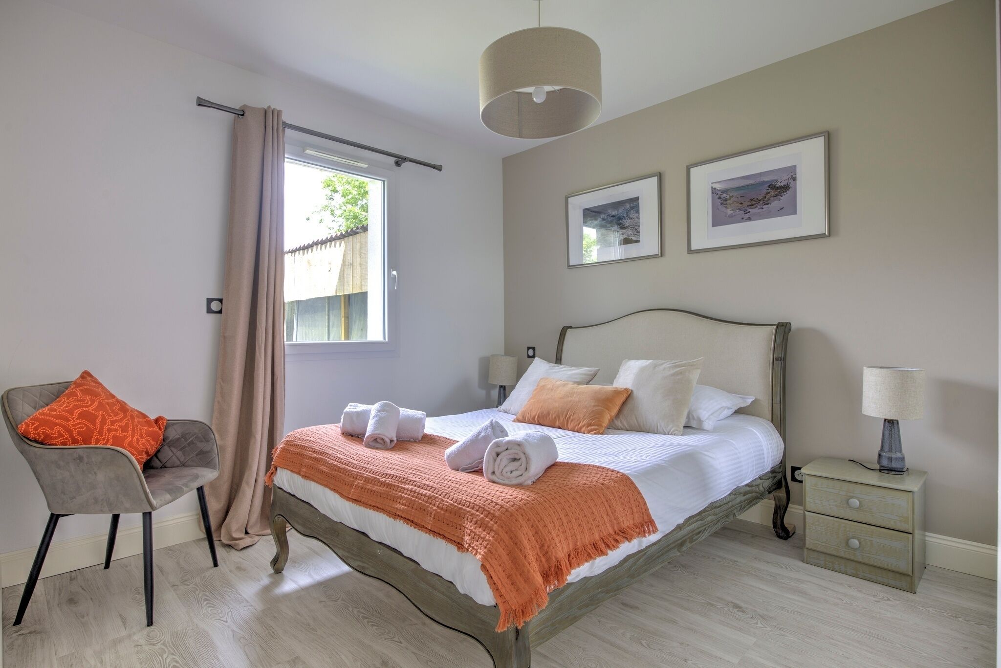 Une chambre à coucher avec un lit, une chaise, une table de chevet et une fenêtre avec des rideaux.