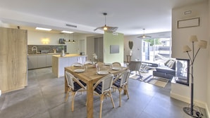 Una cocina moderna con comedor, que incluye una mesa y sillas de madera, una isla de cocina y un amplio ventanal que proporciona luz natural.