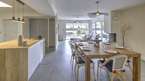 Una cocina moderna con isla de madera, mesa de comedor con sillas e iluminación colgante.