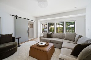 Una sala de estar moderna con un sofá modular, una mesa de centro y una puerta corrediza que da a un balcón.