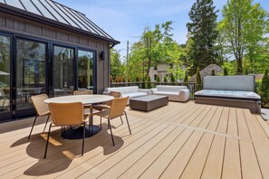 A deck with a table and chairs, a sofa, and a hot tub.