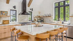 Una cocina moderna con una isla grande, vigas de madera y vistas al exterior.