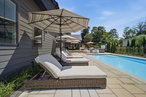 A poolside area with lounge chairs and umbrellas. - Newly built luxury home with pool, hot tub, McKinley Beach access (Union Pier)