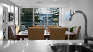 Un espace repas moderne doté d’une grande fenêtre, d’une table à manger et de chaises.