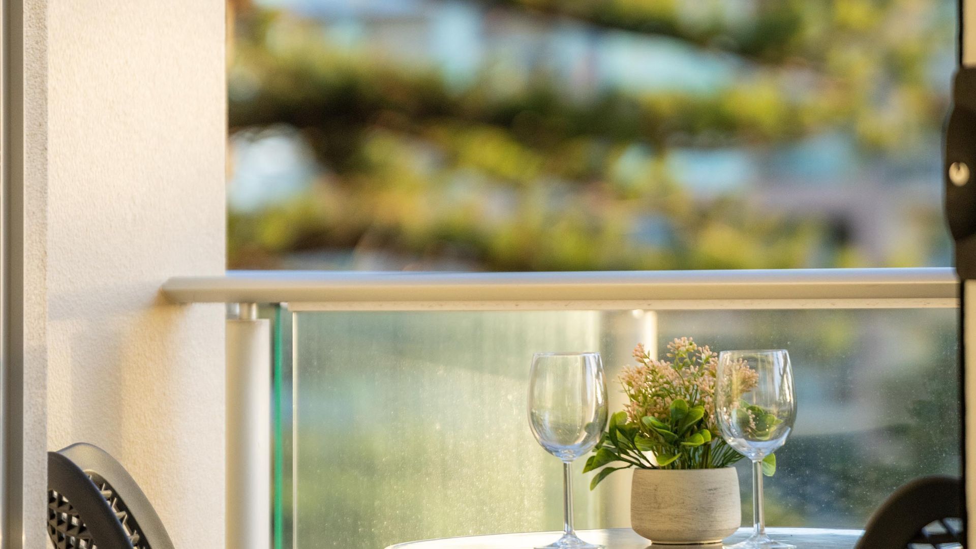 A table with two wine glasses and a small plant on a window sill.
