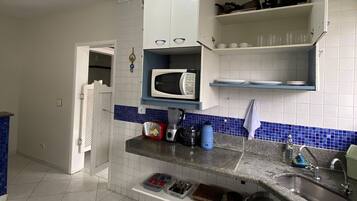 A kitchen with white cabinets, a microwave, a blender, and a sink.