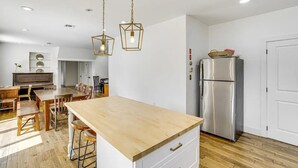 Et moderne køkken med en central ø, et stålskab og hængende lamper.