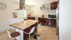 A modern kitchen with a central island, bar stools, a stove, and a microwave.
