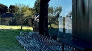 Un edificio moderno con una amplia fachada de vidrio, techo inclinado y zona de terraza de madera.