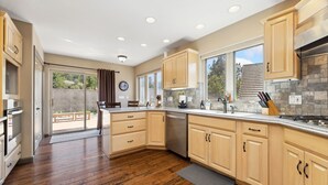 A modern kitchen with wooden cabinets, a dishwasher, and a large window.