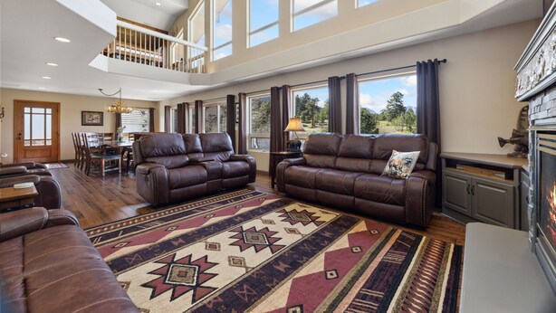 A spacious living room with leather sofas, a large rug, and a fireplace.