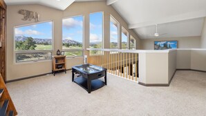 A spacious room with large windows offering mountain views, a foosball table, and a wooden shelf.