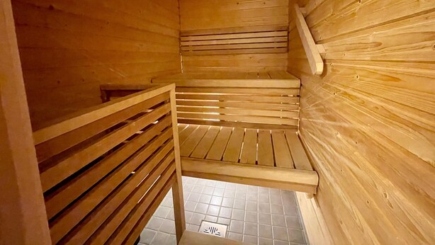 Una sauna de madera con suelo inclinado y un banco.