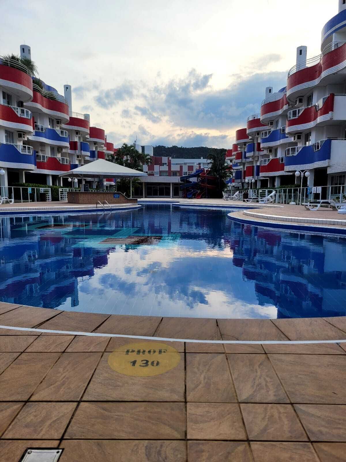 A swimming pool with a tiled deck, surrounded by multi-story buildings with balconies.