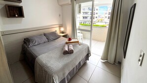 A bedroom with a bed, bedside table, and a view of the outside balcony.