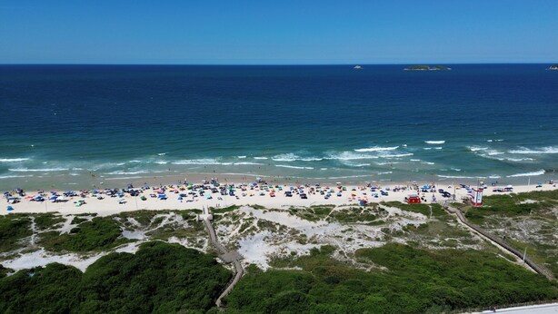 A beach with a wooden walkway leading to the shore, a lifeguard tower, and a clear view of the ocean.